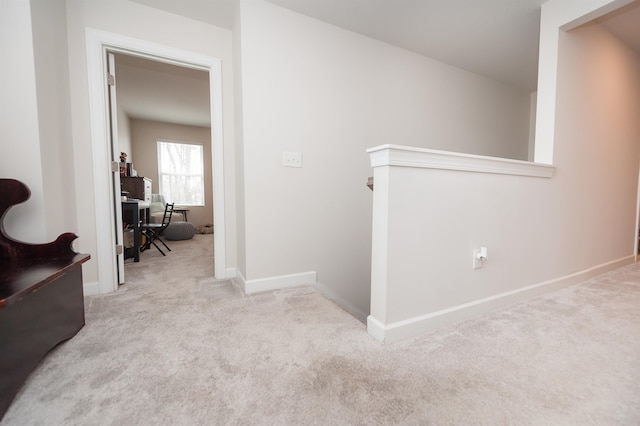 hall featuring an upstairs landing, baseboards, and carpet floors