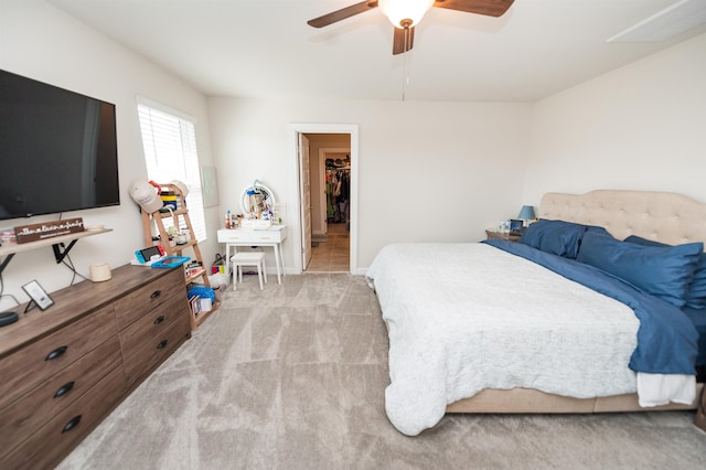 bedroom featuring a walk in closet, baseboards, carpet, and a ceiling fan