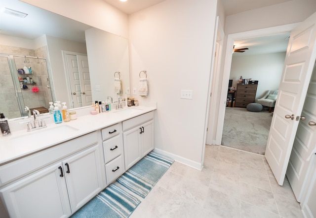 bathroom with double vanity, a stall shower, baseboards, and a sink