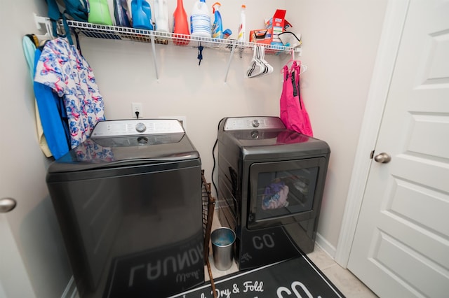 washroom featuring washer and clothes dryer, laundry area, tile patterned floors, and baseboards