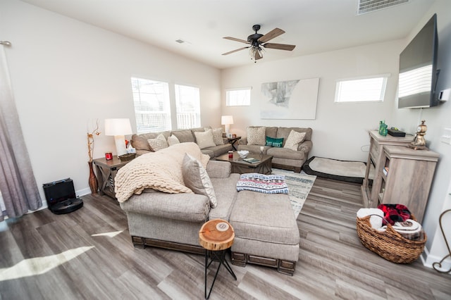 living area featuring wood finished floors, a ceiling fan, visible vents, and baseboards