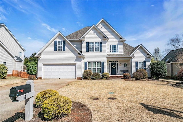 traditional-style house featuring a front lawn, an attached garage, driveway, and fence