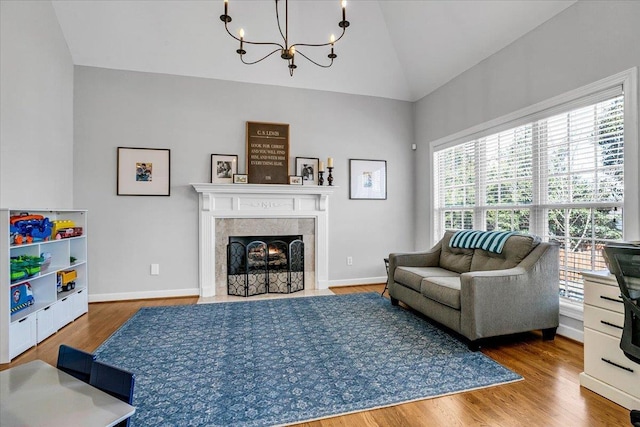 living area featuring a chandelier, lofted ceiling, baseboards, and wood finished floors