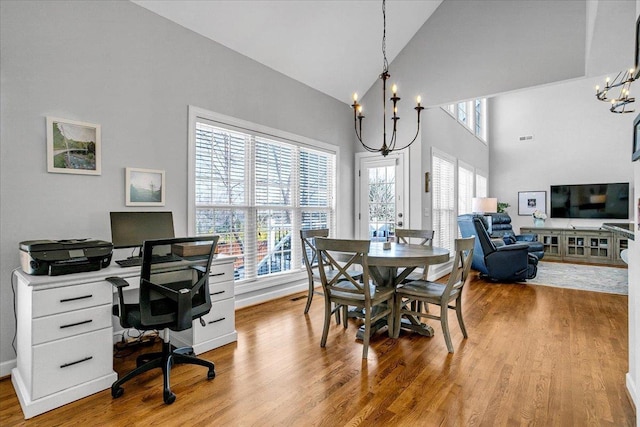 dining room featuring high vaulted ceiling, an inviting chandelier, and wood finished floors