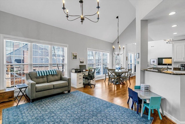 living room with high vaulted ceiling, wood finished floors, recessed lighting, an inviting chandelier, and baseboards