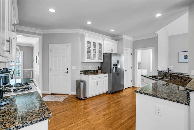 kitchen featuring light wood finished floors, stainless steel fridge, white cabinetry, and glass insert cabinets