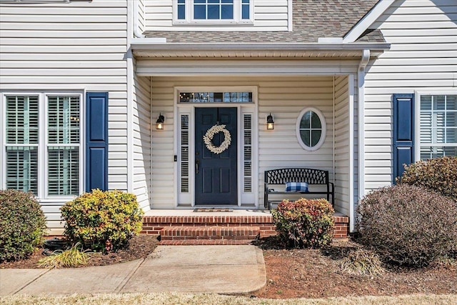 view of exterior entry featuring a porch and roof with shingles