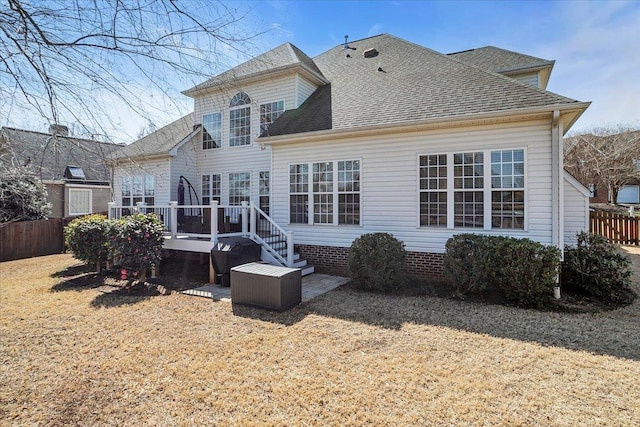 rear view of house with a shingled roof, a yard, fence, and a wooden deck