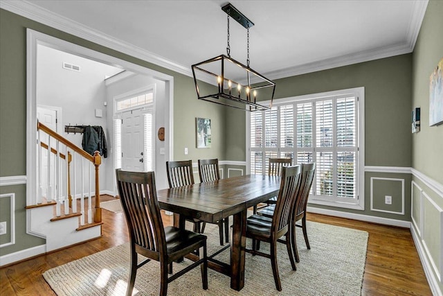 dining room featuring visible vents, crown molding, stairs, an inviting chandelier, and wood finished floors