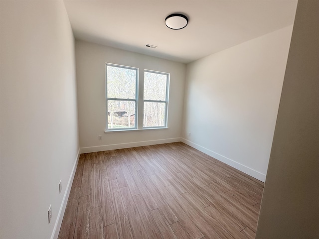 spare room with visible vents, wood finished floors, and baseboards