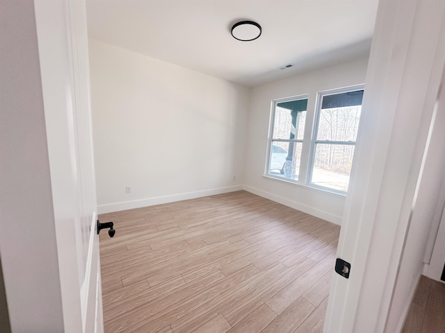 unfurnished room featuring visible vents, light wood-style flooring, and baseboards