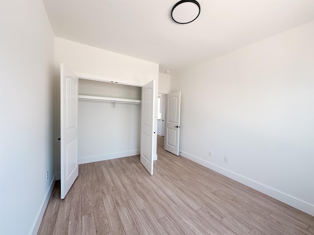 unfurnished bedroom with light wood-style floors, a closet, and baseboards