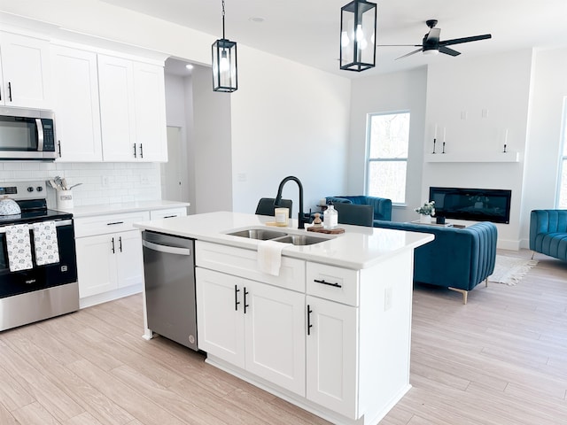 kitchen featuring a ceiling fan, a sink, light countertops, appliances with stainless steel finishes, and open floor plan