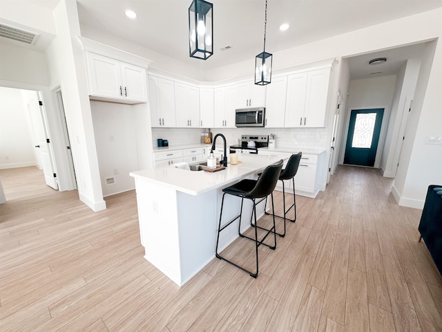 kitchen with a sink, light wood-type flooring, visible vents, and stainless steel appliances