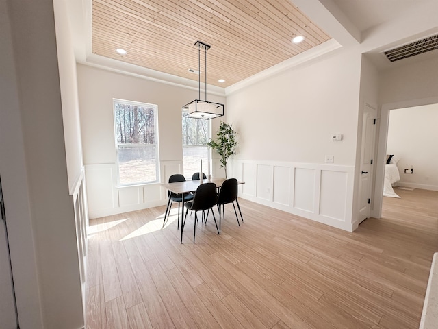 dining room with light wood finished floors, visible vents, wooden ceiling, and a decorative wall