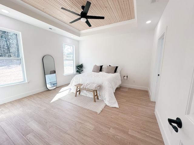 bedroom featuring light wood finished floors, wooden ceiling, and a raised ceiling