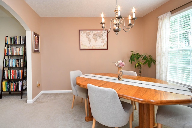 dining space featuring plenty of natural light, light colored carpet, arched walkways, and a chandelier