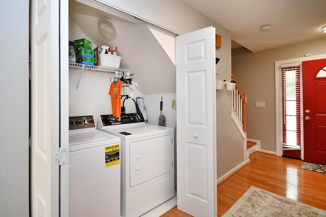 laundry area with light wood finished floors, laundry area, washing machine and dryer, and baseboards