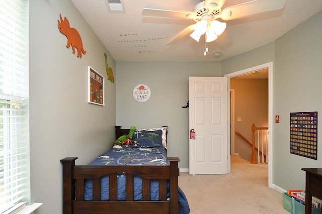 bedroom with a ceiling fan, light colored carpet, visible vents, and baseboards