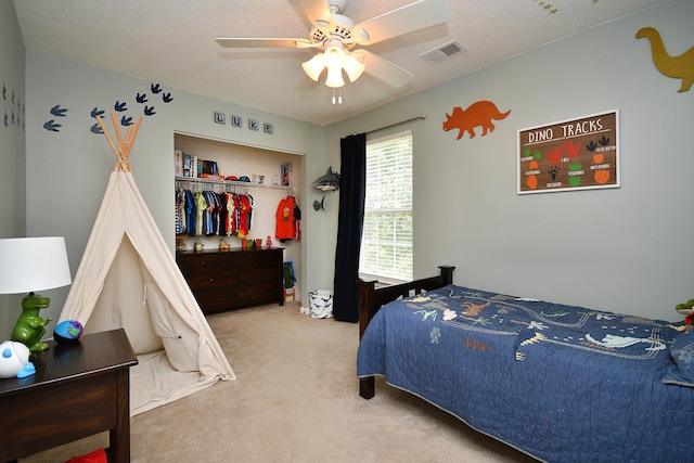 bedroom with visible vents, ceiling fan, carpet, a closet, and a textured ceiling