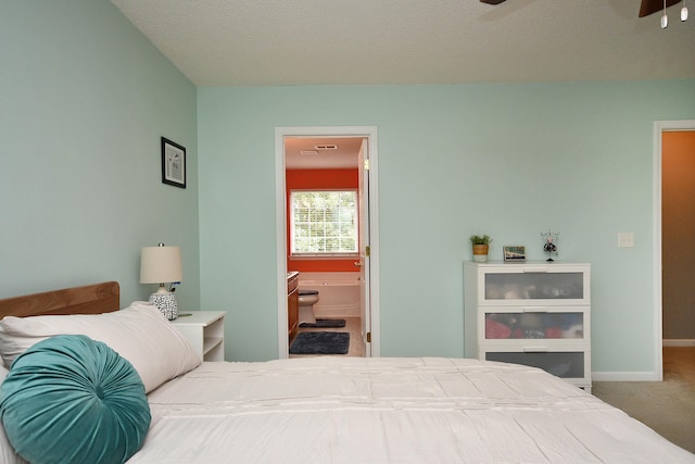 carpeted bedroom featuring baseboards and ensuite bathroom