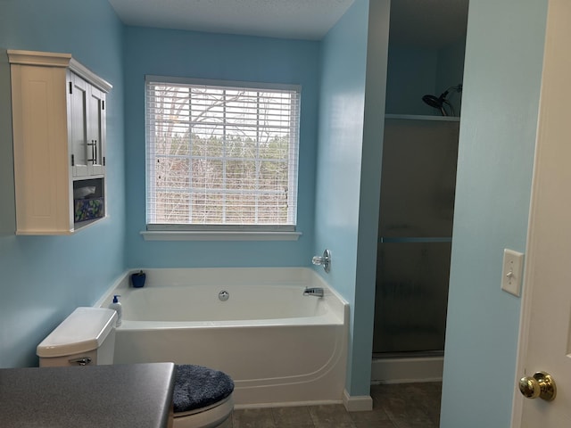 bathroom featuring tile patterned floors, a garden tub, toilet, and a shower stall