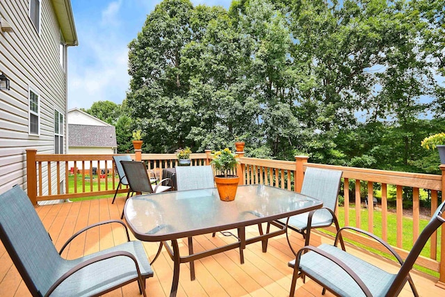 wooden terrace featuring outdoor dining area and a yard