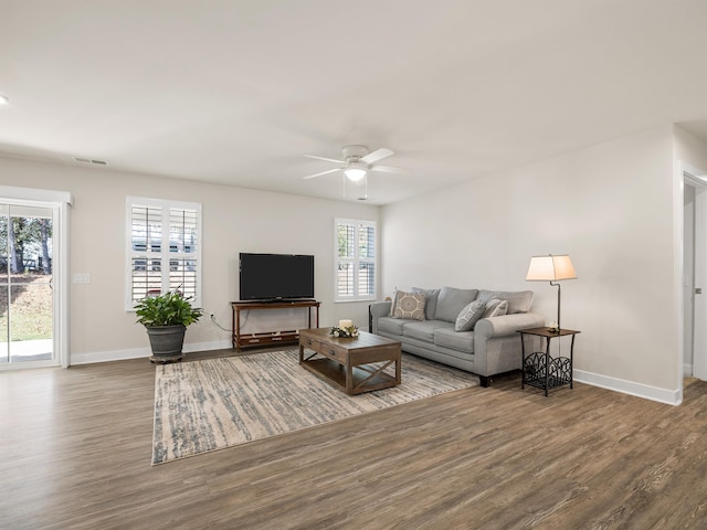 living area featuring baseboards, wood finished floors, visible vents, and ceiling fan