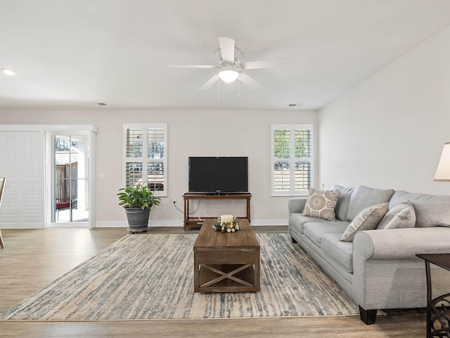 living area with a ceiling fan, visible vents, wood finished floors, and baseboards