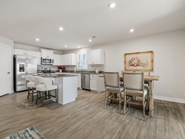 kitchen featuring a breakfast bar, tasteful backsplash, a kitchen island, stainless steel appliances, and white cabinets