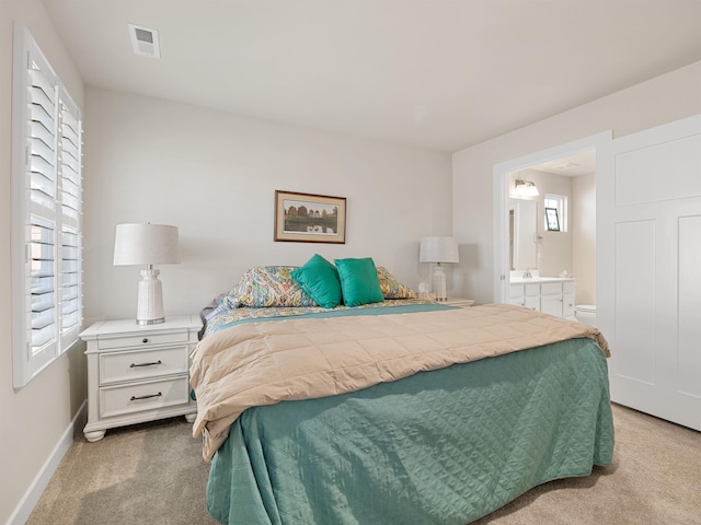 bedroom with baseboards, light carpet, visible vents, and connected bathroom