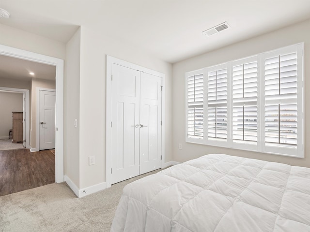 carpeted bedroom with visible vents, baseboards, and a closet