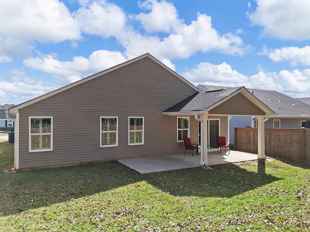 rear view of property featuring a patio area, a lawn, and fence