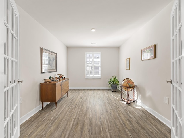 living area featuring french doors, baseboards, and wood finished floors