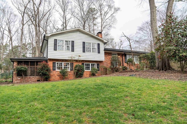 tri-level home featuring a front yard, brick siding, and a chimney