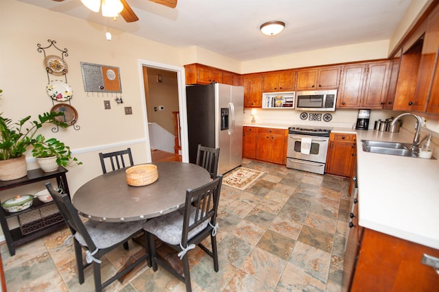 kitchen featuring a sink, stainless steel appliances, brown cabinets, and ceiling fan