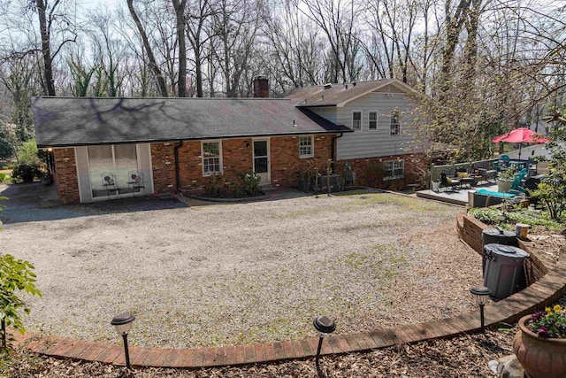 back of property featuring brick siding and a chimney