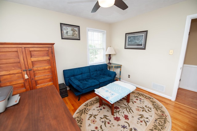 living area featuring visible vents, baseboards, a ceiling fan, and wood finished floors