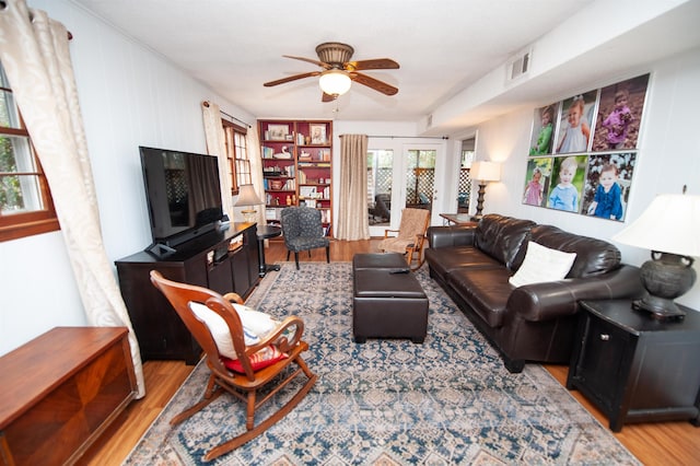 living room with visible vents, light wood-type flooring, and a ceiling fan