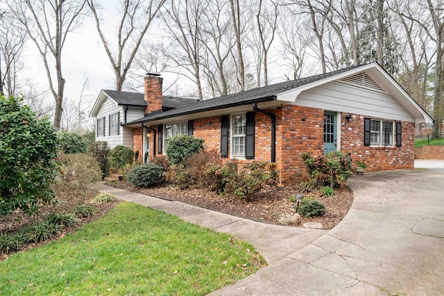 split level home featuring driveway, brick siding, and a chimney