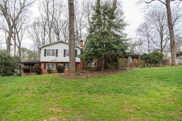 view of front of home with brick siding, a chimney, and a front lawn