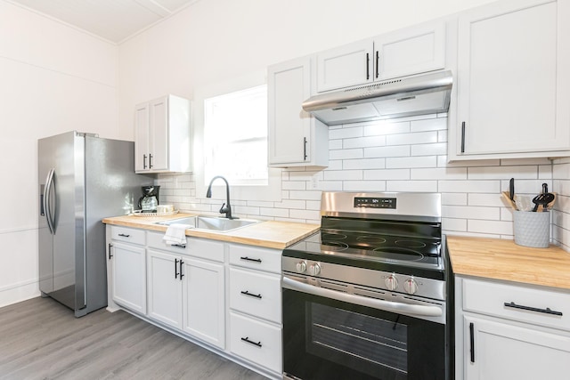 kitchen featuring under cabinet range hood, butcher block countertops, decorative backsplash, stainless steel appliances, and a sink