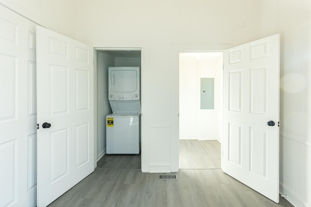 washroom with stacked washer / dryer, visible vents, electric panel, laundry area, and wood finished floors