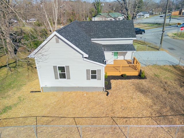 exterior space featuring roof with shingles and fence