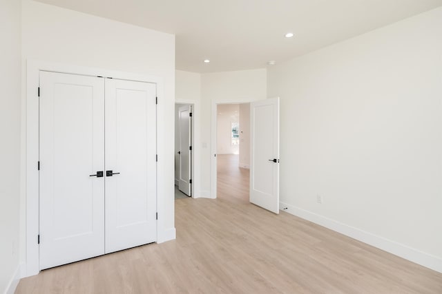 unfurnished bedroom with a closet, recessed lighting, light wood-type flooring, and baseboards
