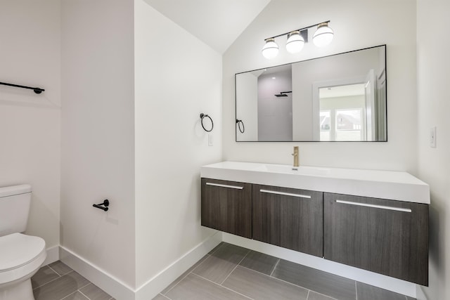 bathroom with baseboards, lofted ceiling, toilet, and vanity