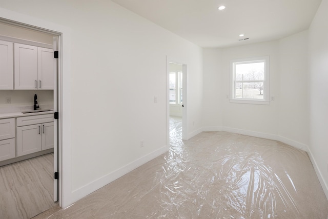 spare room with recessed lighting, baseboards, and a sink