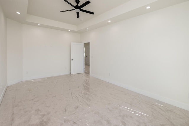 unfurnished room with a tray ceiling, recessed lighting, baseboards, and ceiling fan