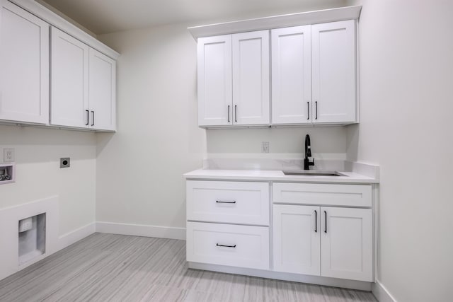 laundry room with baseboards, hookup for a washing machine, cabinet space, hookup for an electric dryer, and a sink