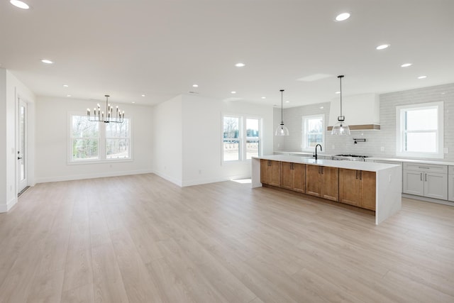 kitchen featuring decorative backsplash, a chandelier, light countertops, and light wood finished floors